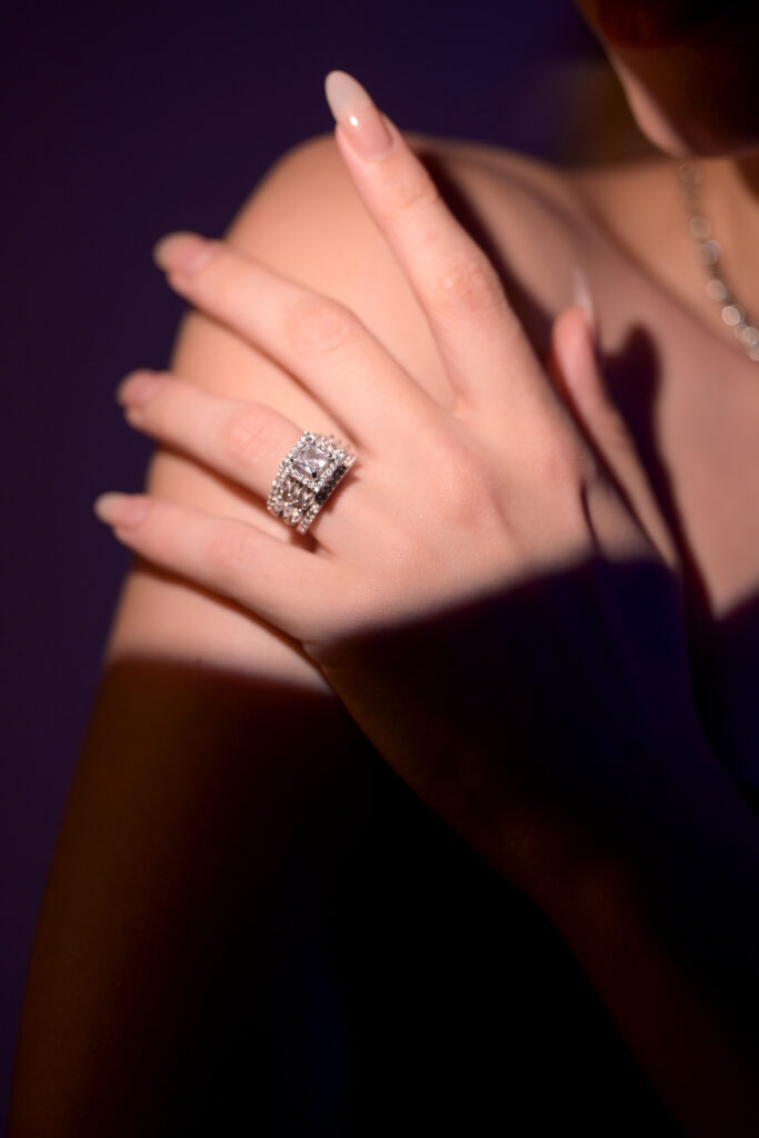 Rhodium-plated Aethelred Ring with rectangular-cut cubic zirconia centre stone, surrounded by halo and triple pavé-set stone rows on a wide band.